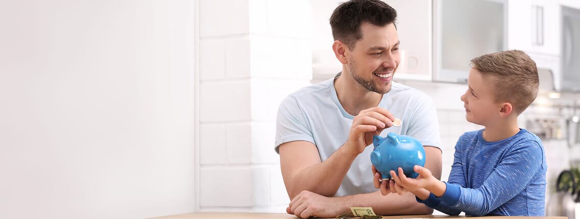 Ojciec uczący dziecko oszczędzania pieniędzy do skarbonki